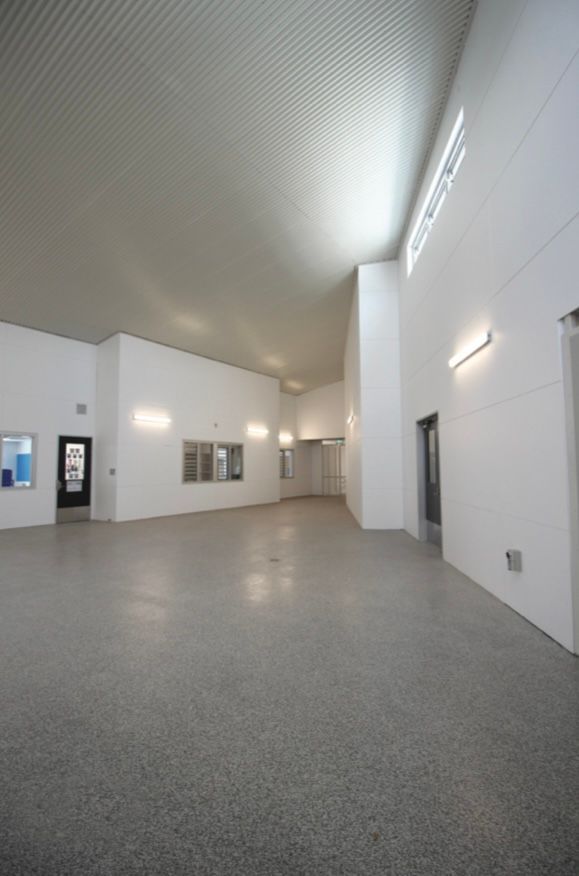 A large empty room with white walls and a gray floor.