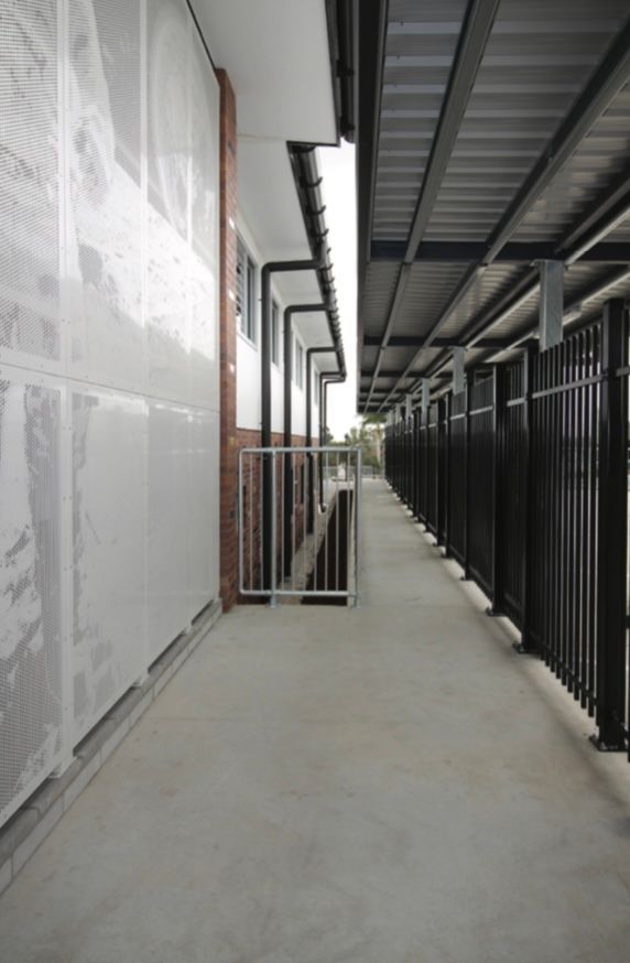 A long hallway between two buildings with a black fence