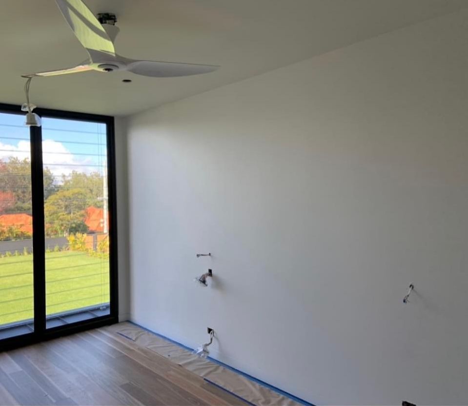 An empty room with a ceiling fan and a large window.