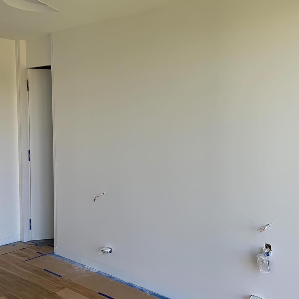 An empty room with a white wall and a wooden floor.