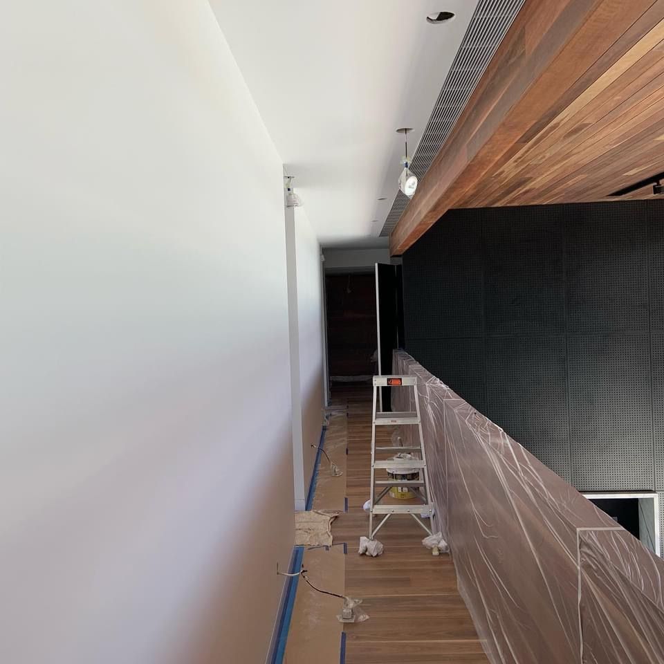 A ladder is sitting in the middle of a hallway covered in plastic.