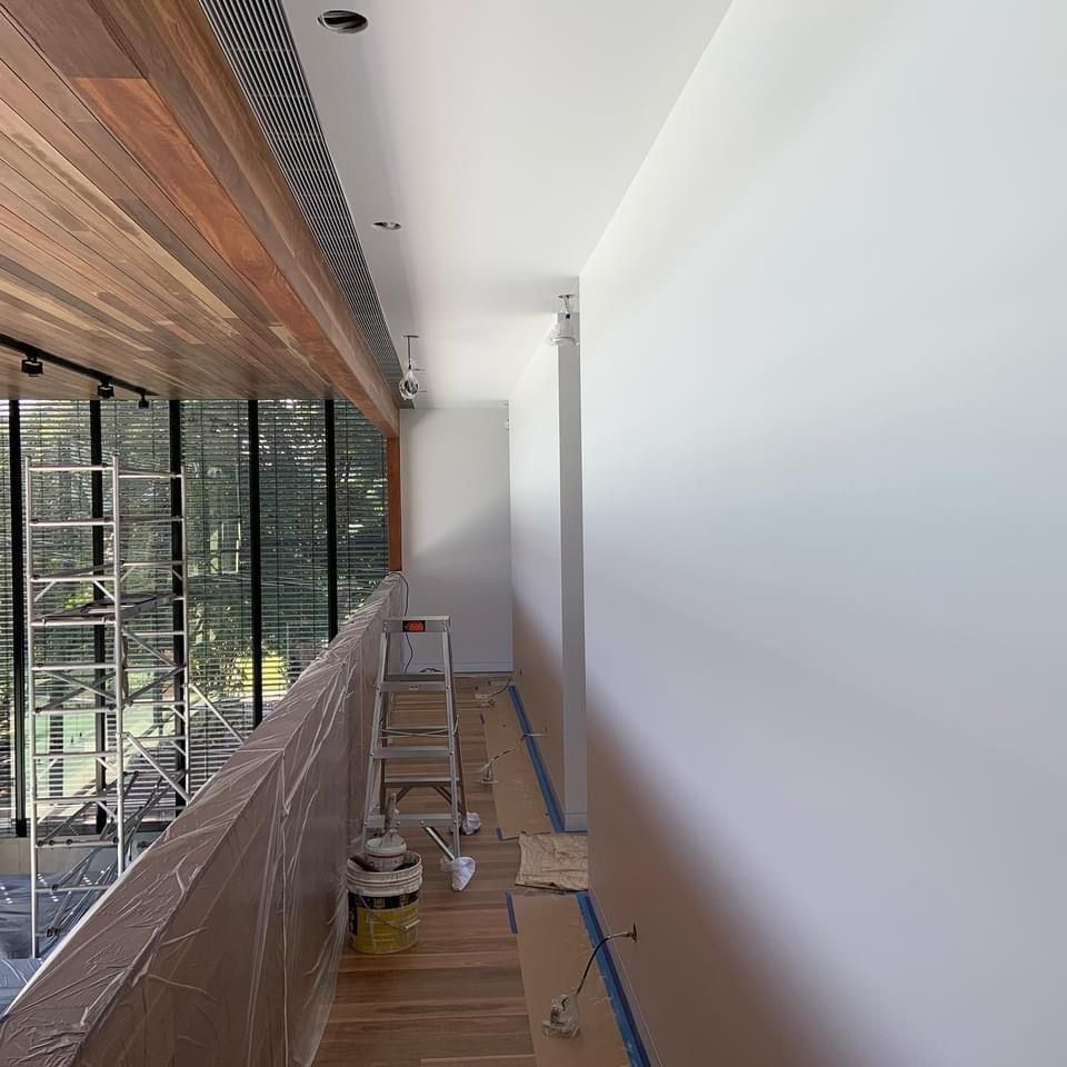 A long hallway with a ladder and buckets of paint