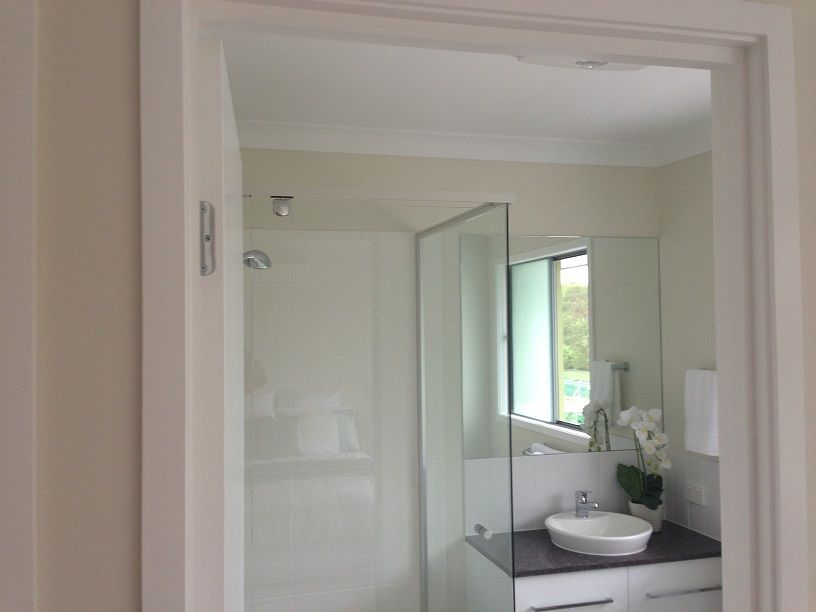 A bathroom with a sink , shower and mirror.