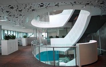 A modern office building with a curved staircase and a reception desk.