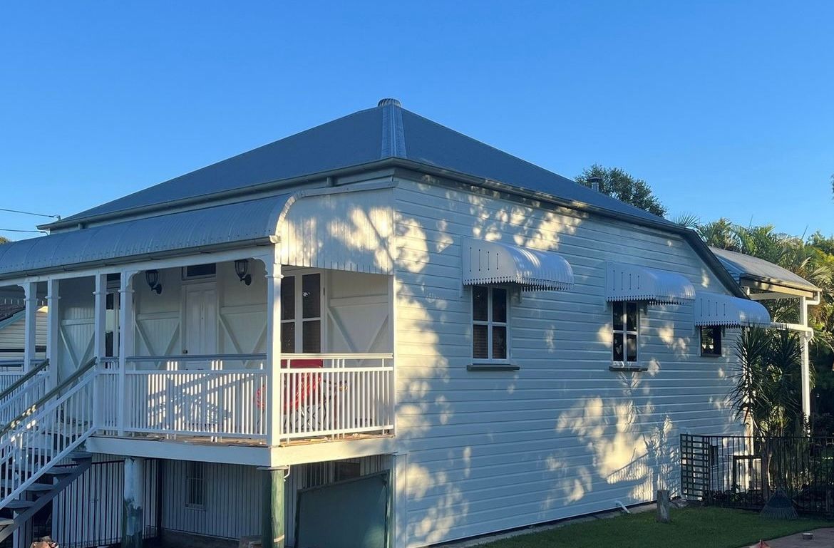 A white house with a porch and stairs on a sunny day.