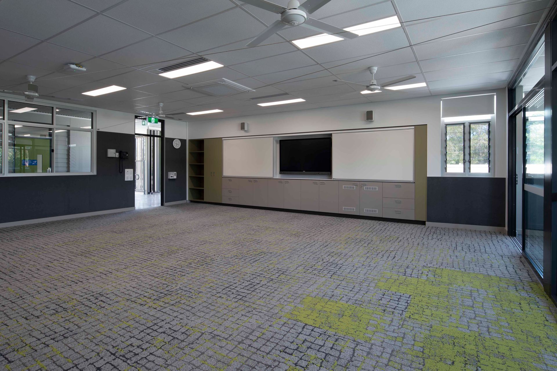 A large empty room with a ceiling fan and a flat screen tv.