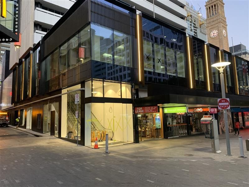 A large building with a lot of windows is on the corner of a city street.