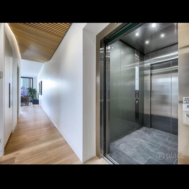 A hallway with a stainless steel elevator in the middle of it.