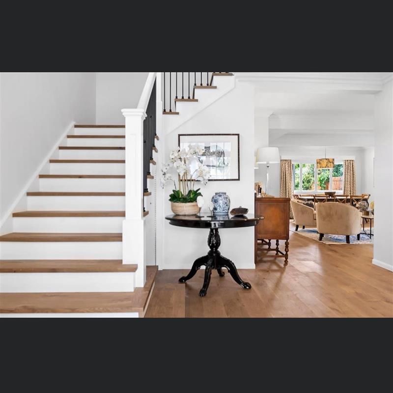 A white staircase with wooden steps and a table in front of it
