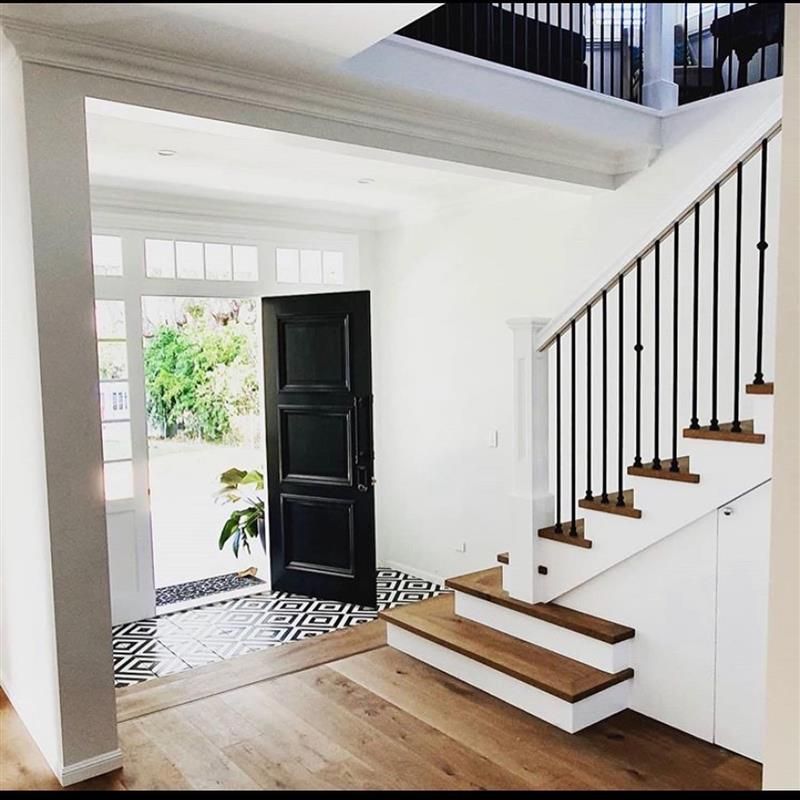 A hallway with stairs and a black door