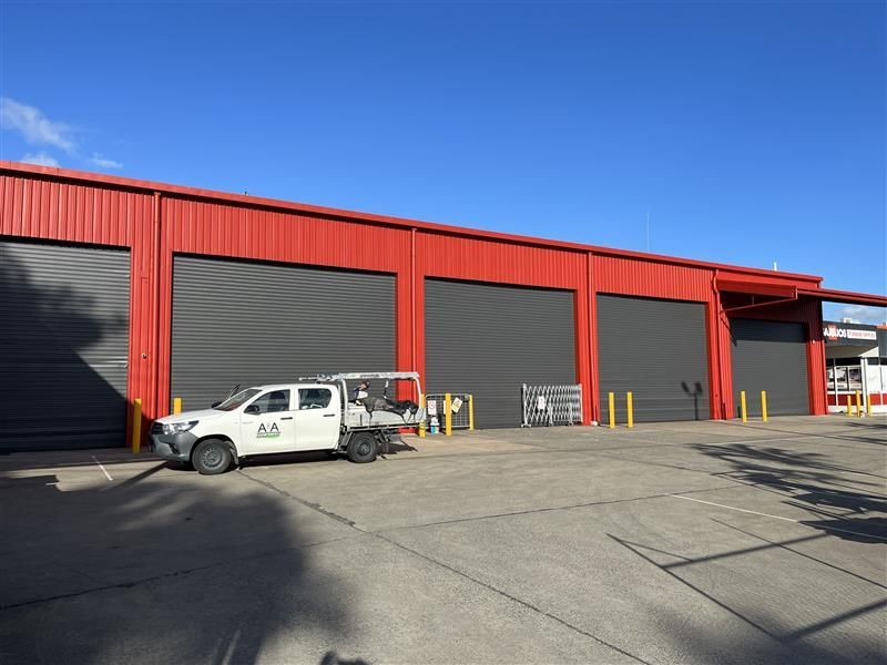 A white truck is parked in front of a red building.