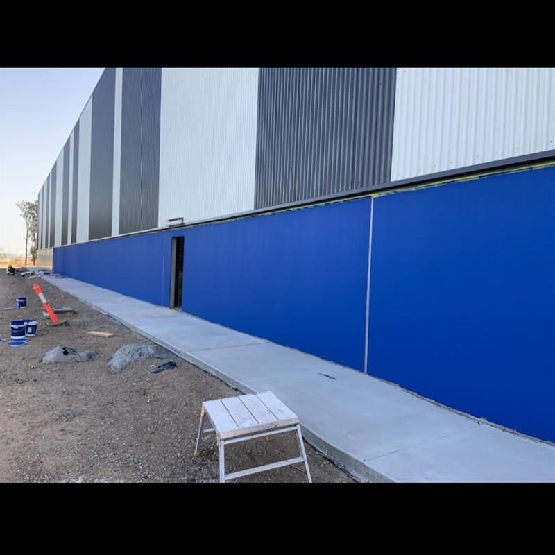 A blue wall is being painted on the side of a building.