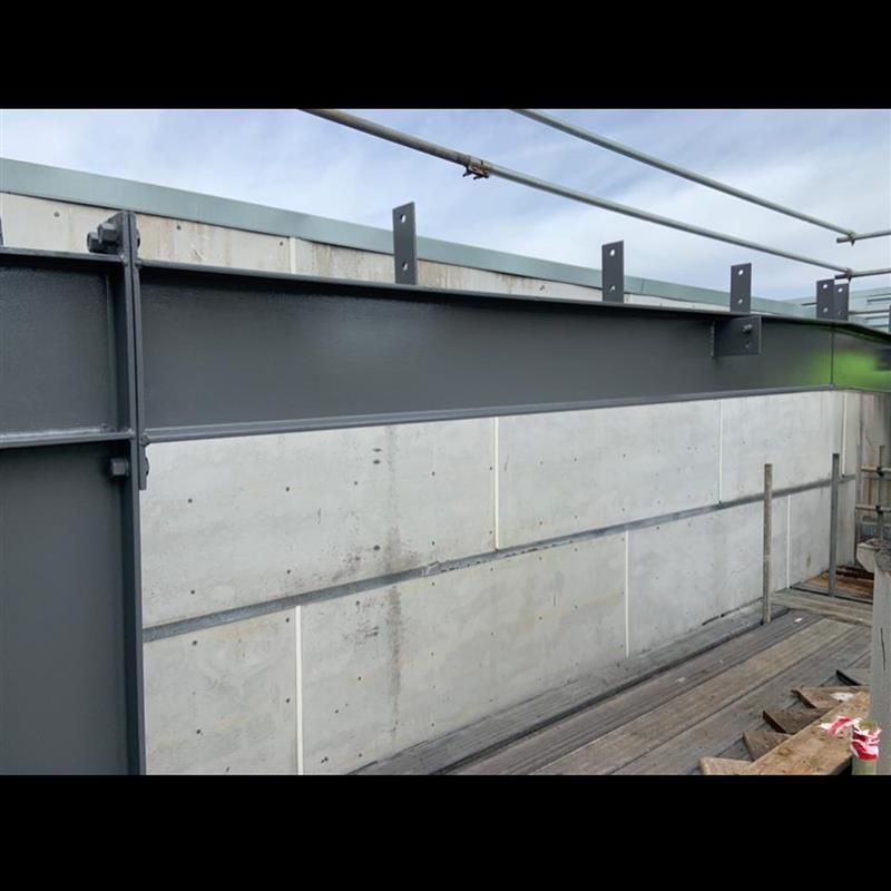 A large metal beam is sitting on top of a concrete wall.