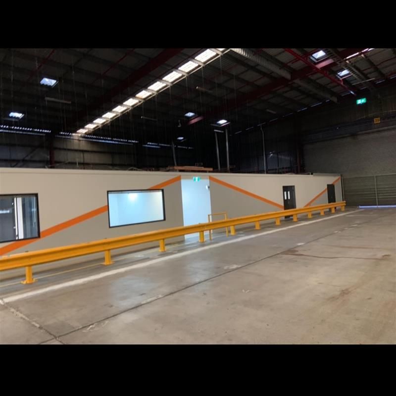 A large warehouse with a concrete floor and a yellow railing