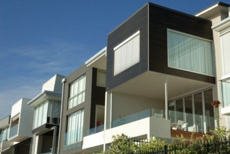 A row of houses with balconies and a blue sky in the background