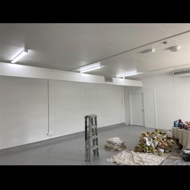 A large room with white walls and a ladder on the floor