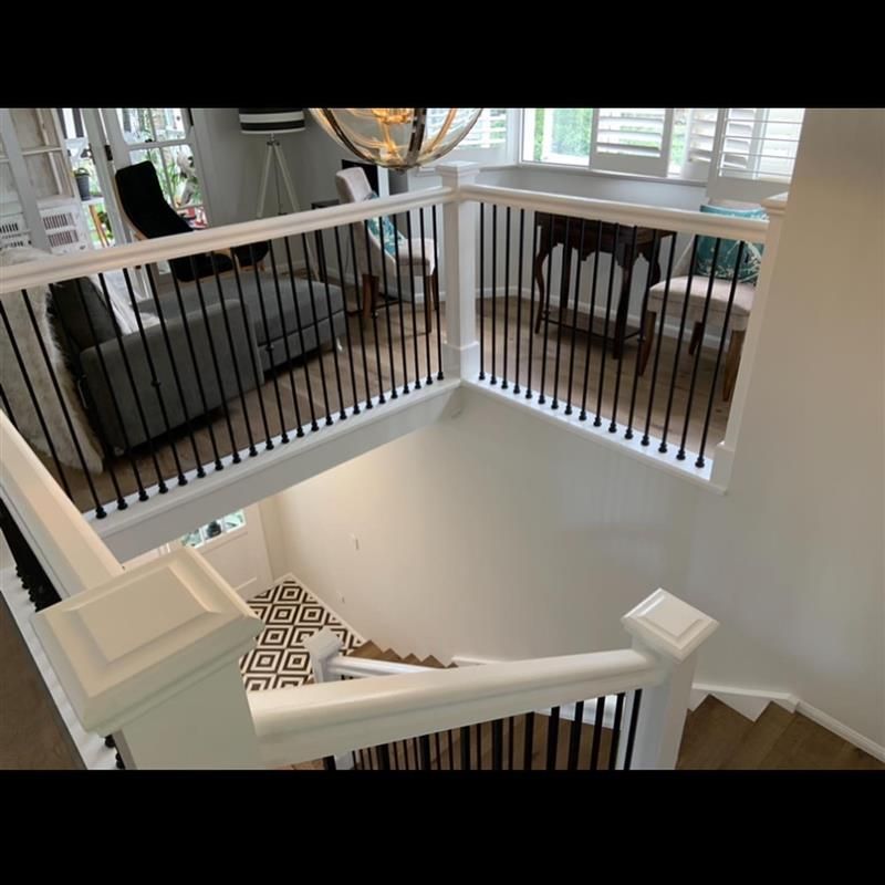 A staircase leading up to a living room with a black railing