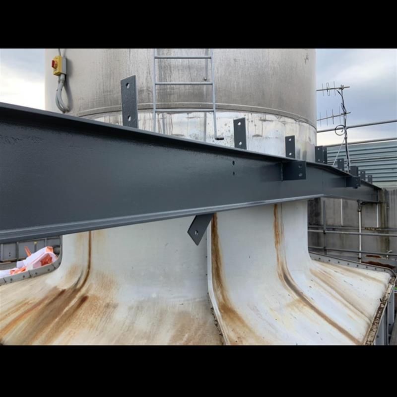 A metal structure is sitting on top of a large white tank.