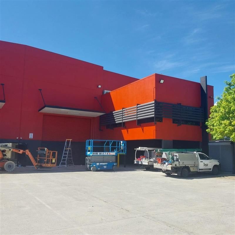 A white truck is parked in front of a large red building