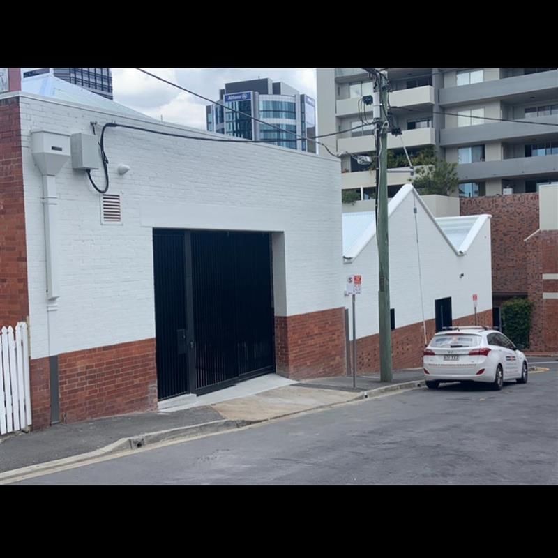 A white car is parked in front of a white building