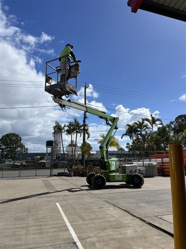 A man is working on a lift in a parking lot.