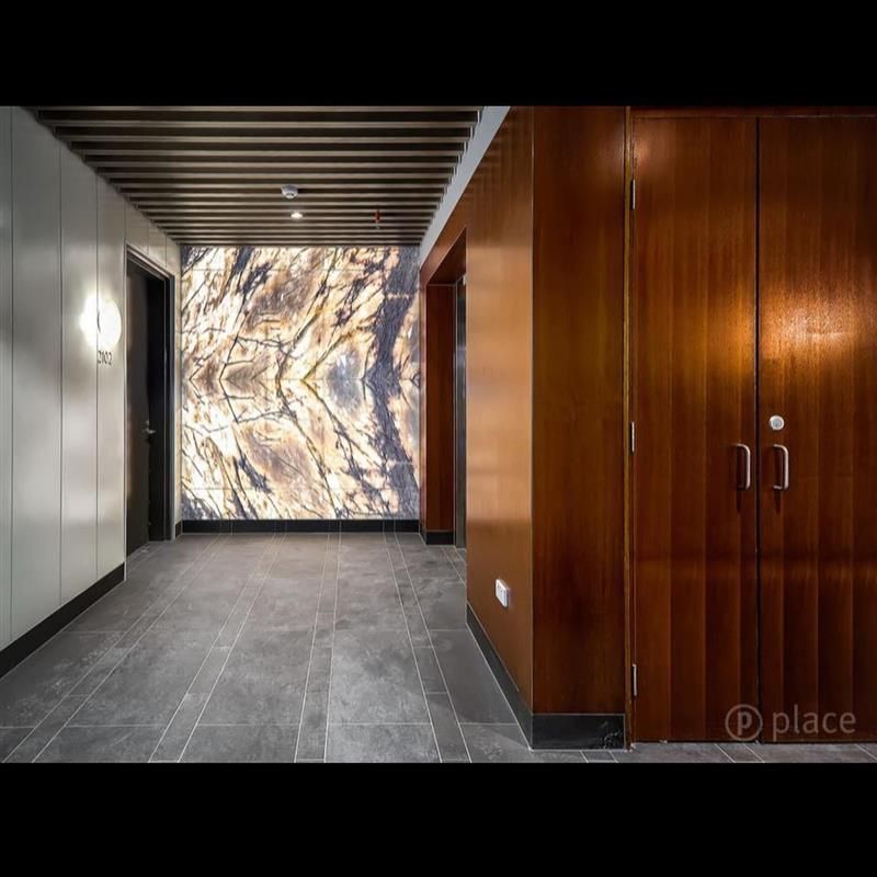A hallway with a wooden door and a marble wall.