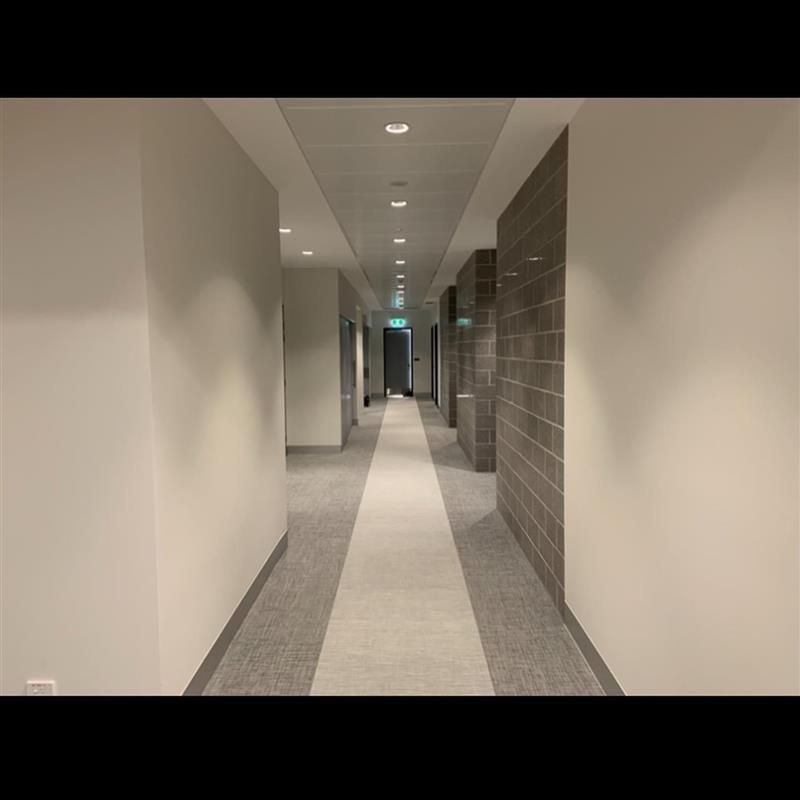 A long hallway in a building with a brick wall and a carpeted floor.