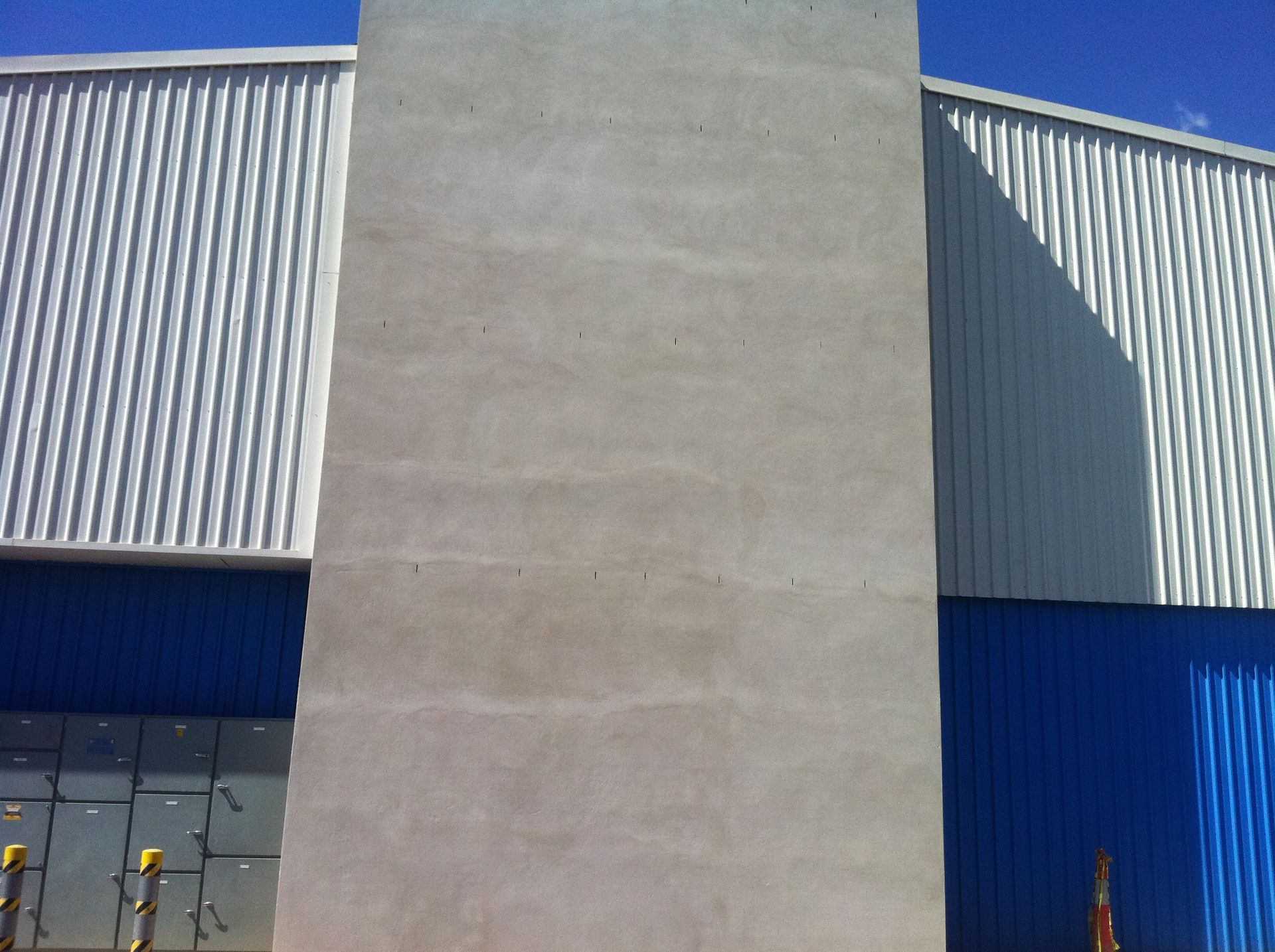 A white and blue building with a concrete pillar in the middle