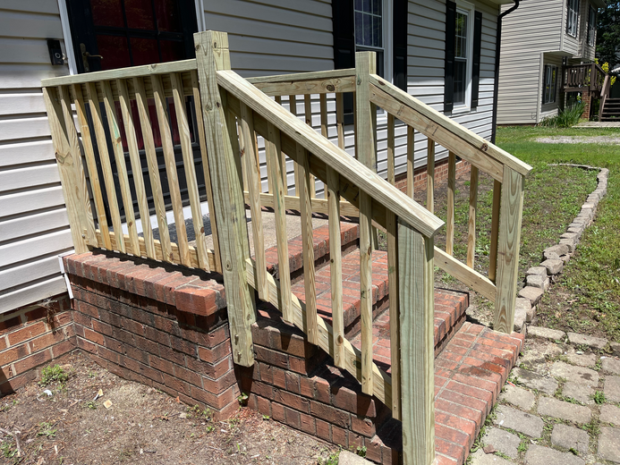 Brick steps with wooden railing leading to a house entrance.
