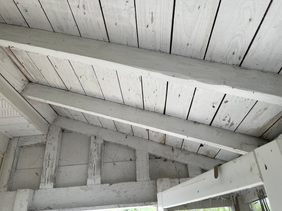 White painted wooden ceiling and beams of a porch.