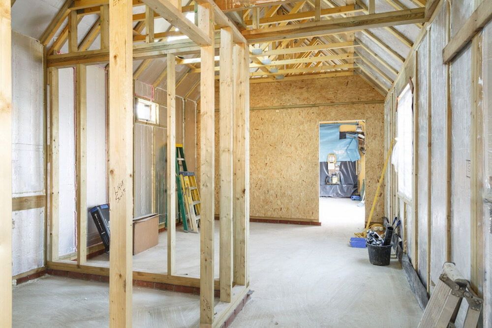 A Room Under Construction With Wooden Beams and a Ladder — Ozi Construction Pty Ltd in Sydney, NSW
