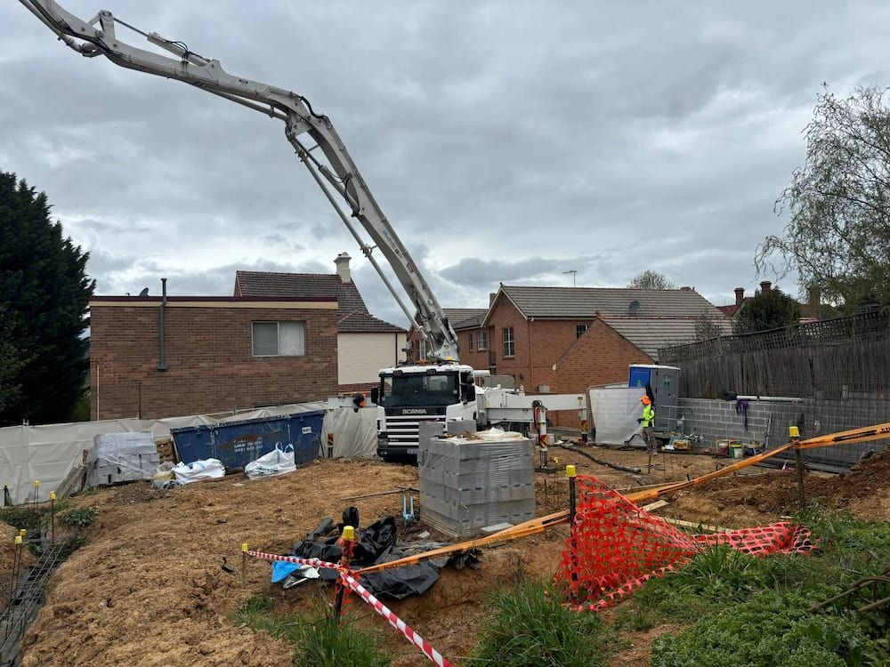 A Concrete Pump is Being Used to Pour Concrete on a Construction Site — Ozi Construction Pty Ltd in Griffith, ACT