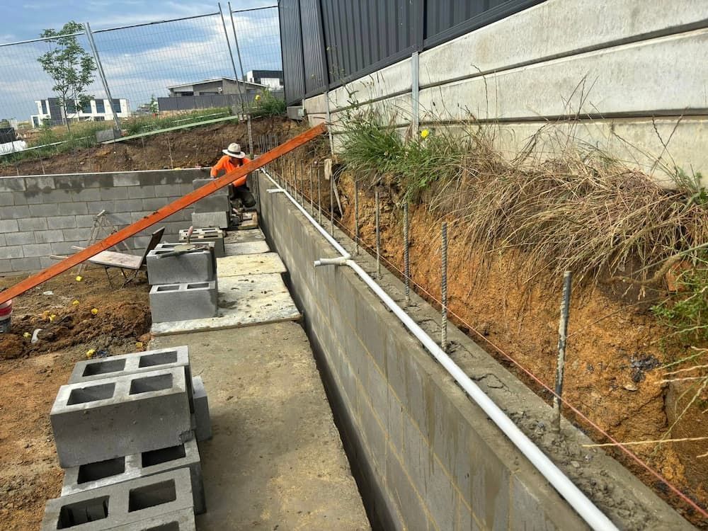 A Concrete Wall is Being Built With Bricks and Pipes — Ozi Construction Pty Ltd in North Sydney, NSW