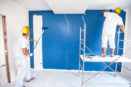 Two Men Are Painting a Blue Wall in a Room — Ozi Construction Pty Ltd in Griffith, ACT