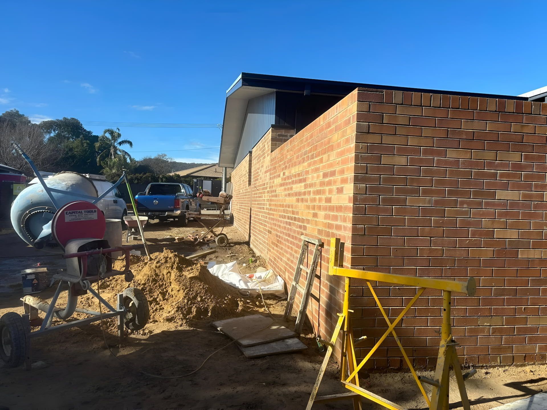 A Blue Car Besides of Under Construction House — Ozi Construction Pty Ltd in Canberra, NSW