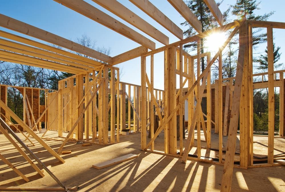 The Sun is Shining Through the Wooden Frames of a House Under Construction — Ozi Construction Pty Ltd in Sydney, NSW