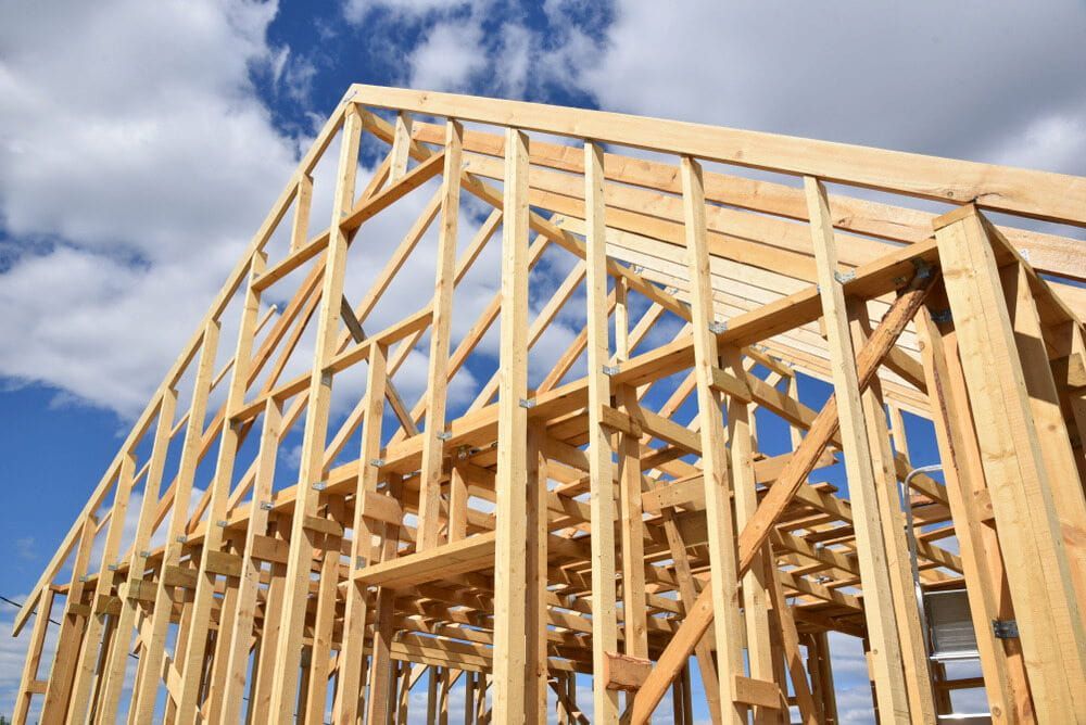 A House is Being Built With Wooden Beams and a Blue Sky in the Background — Ozi Construction Pty Ltd in Mosman, NSW