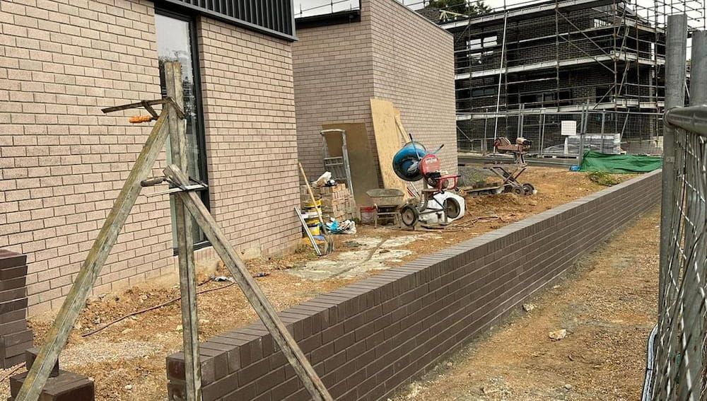 A Brick Wall is Being Built in Front of a Building Under Construction — Ozi Construction Pty Ltd in Bondi, NSW