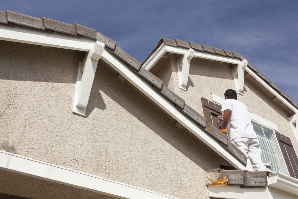 A Man is Painting the Side of a House — Ozi Construction Pty Ltd in Mosman, NSW