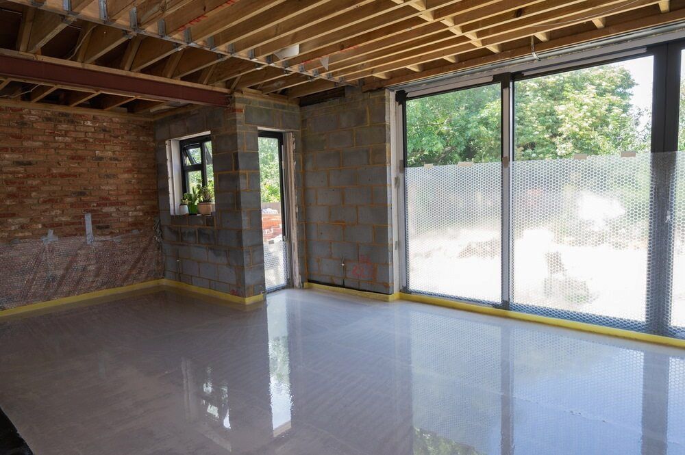 A Large Empty Room With a Lot of Windows and a Brick Wall — Ozi Construction Pty Ltd in Griffith, ACT