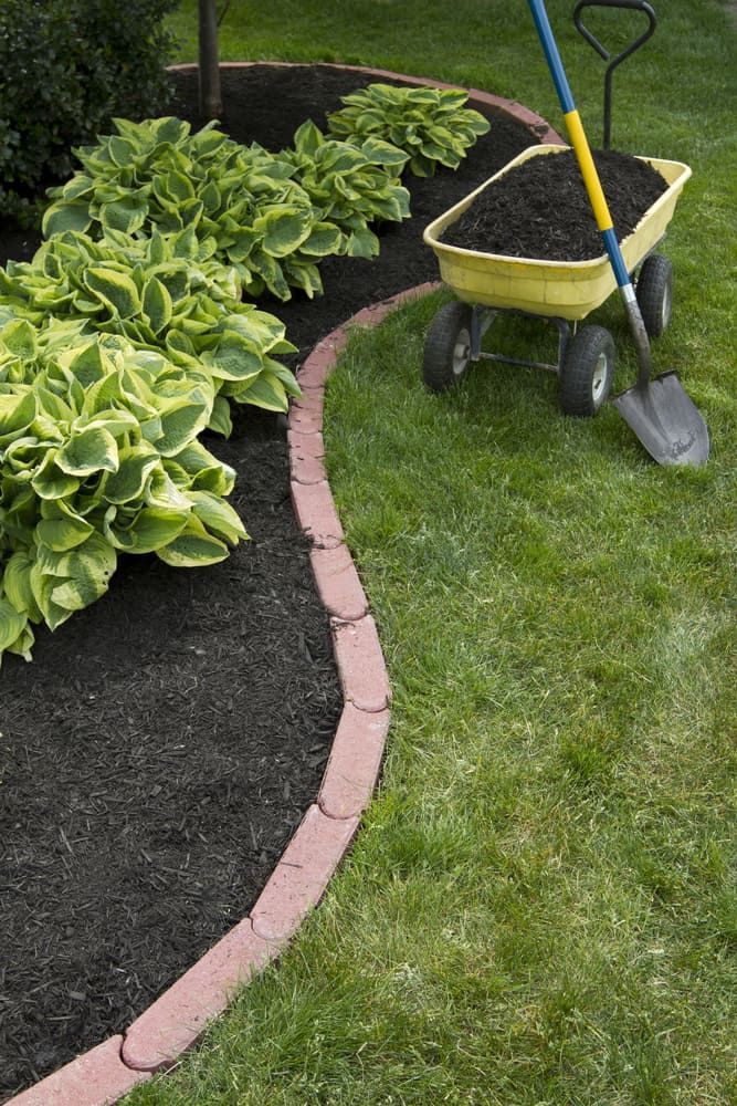 A Wheelbarrow Filled With Dirt and a Shovel in a Garden — Ozi Construction Pty Ltd in North Sydney, NSW