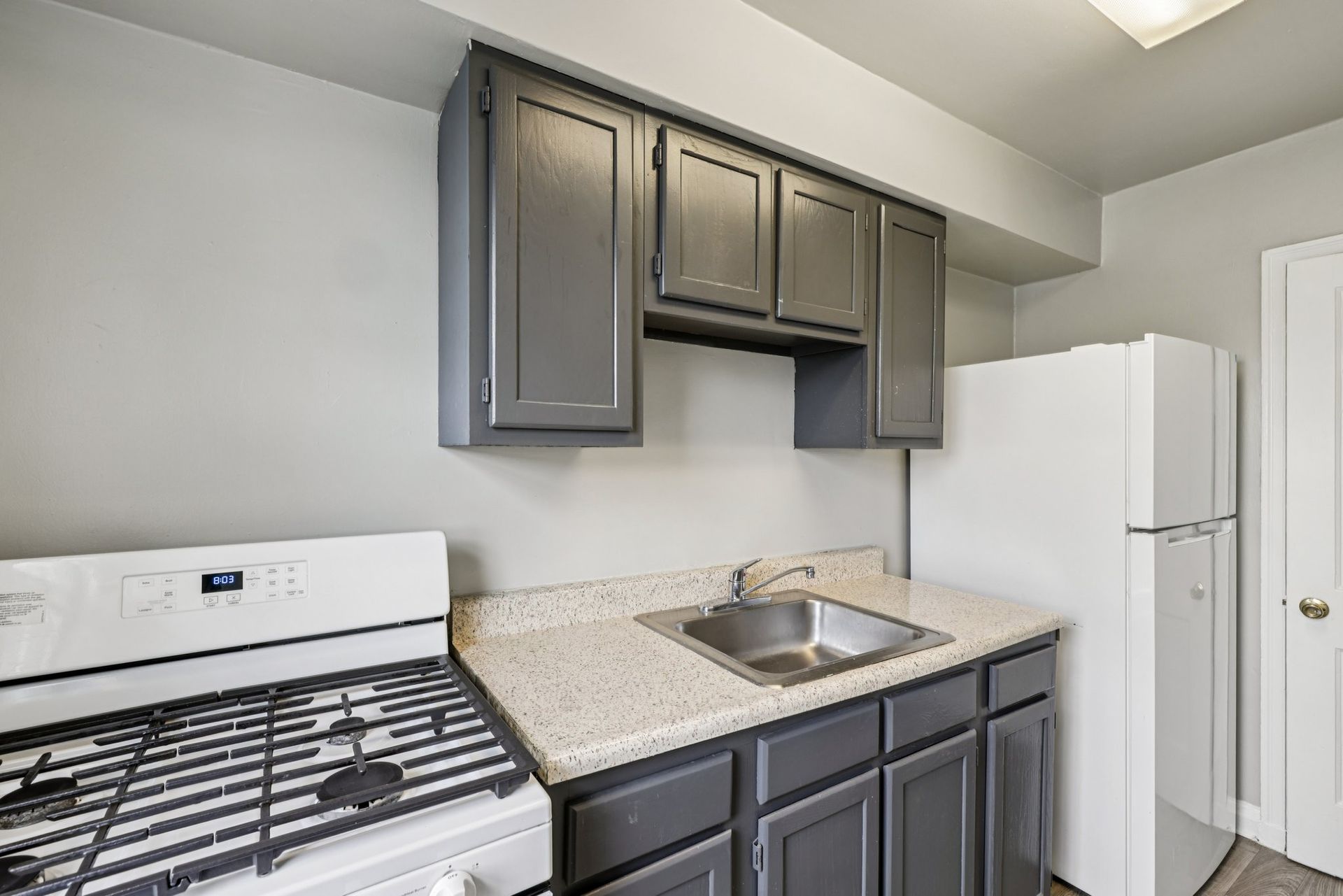 Kitchen with gray cabinets, white appliances, and a gas stove.