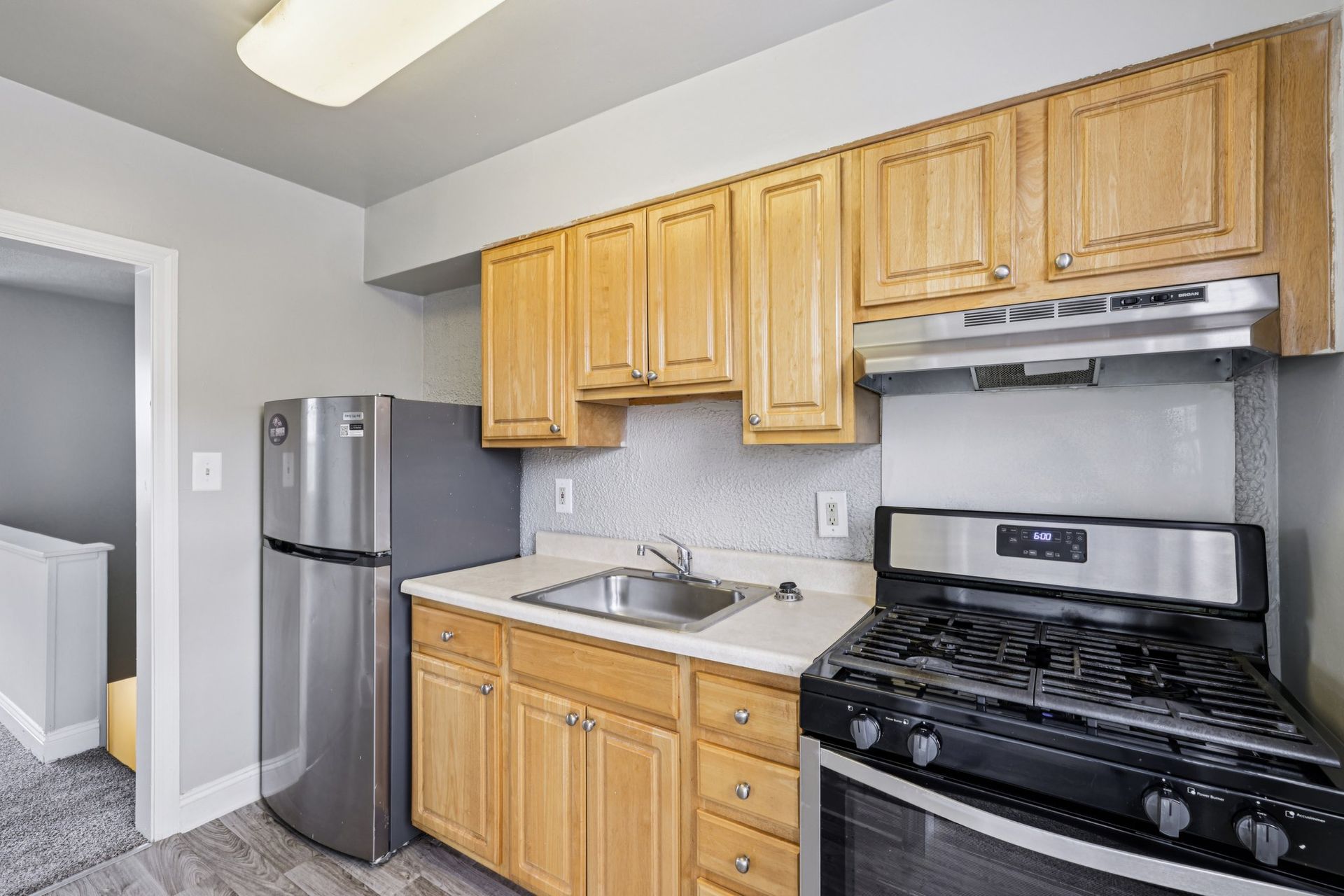 Small kitchen with wooden cabinets, stainless steel appliances, and a gray-painted wall.