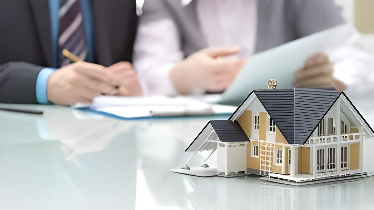 A Couple of People Are Sitting at a Table With a Model House on It — Lifestyle Finance Mackay in Mackay, QLD
