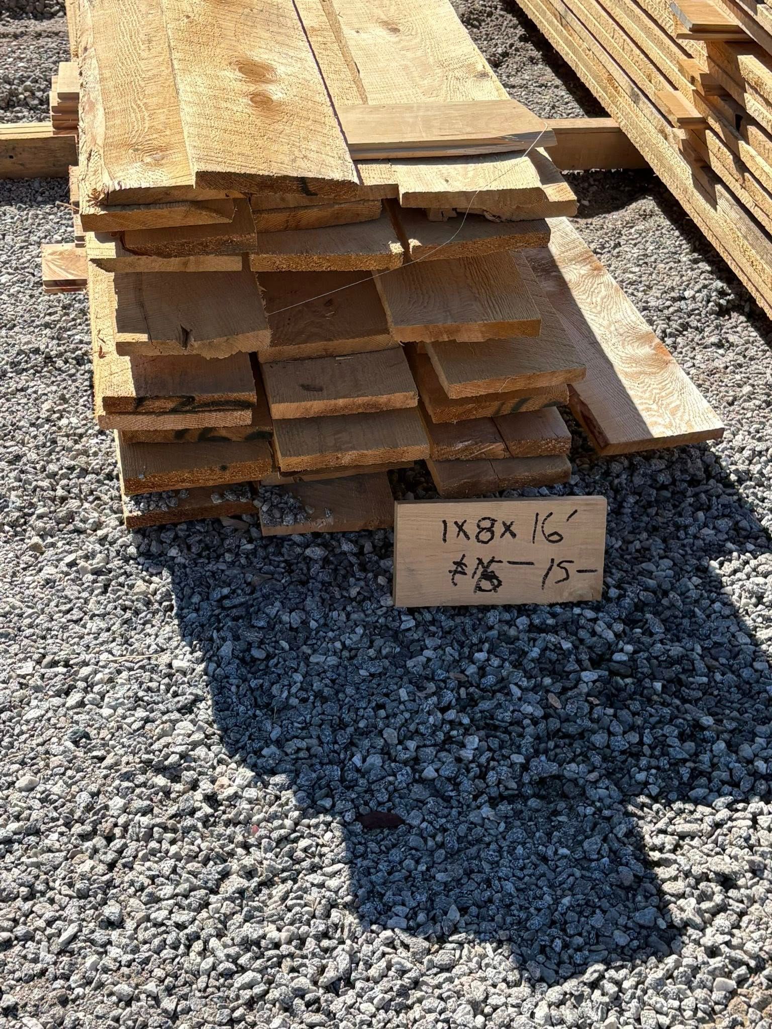 Pile of weathered wooden planks on gravel.