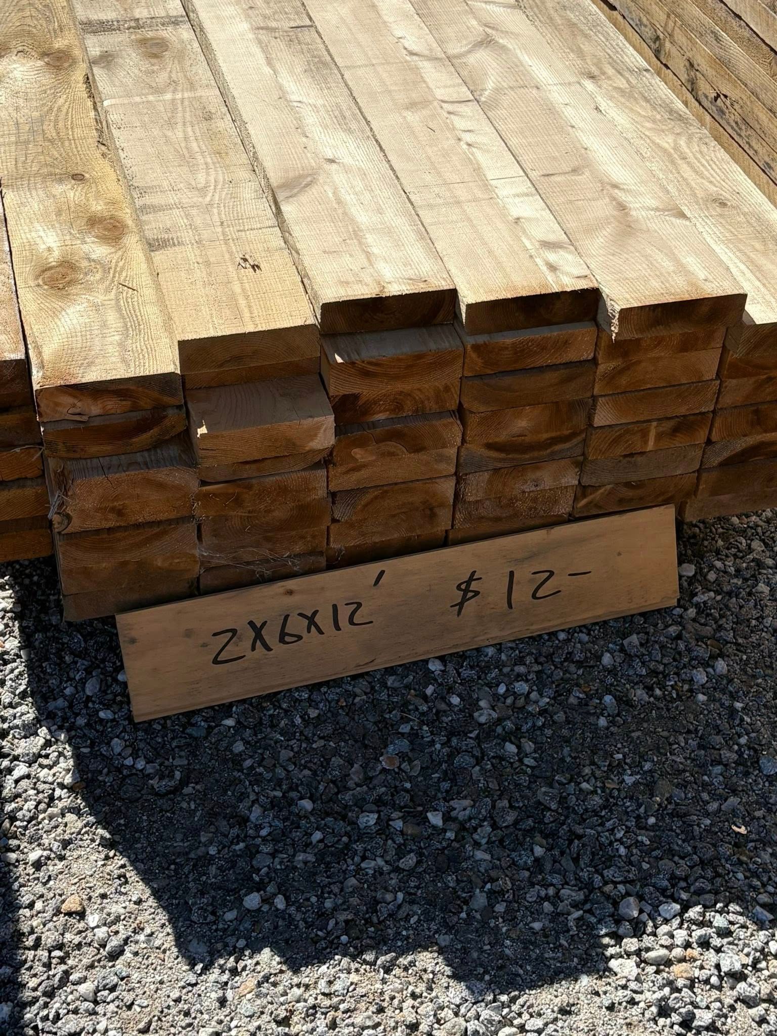 Pile of weathered wooden planks with a sign indicating dimensions and a price.
