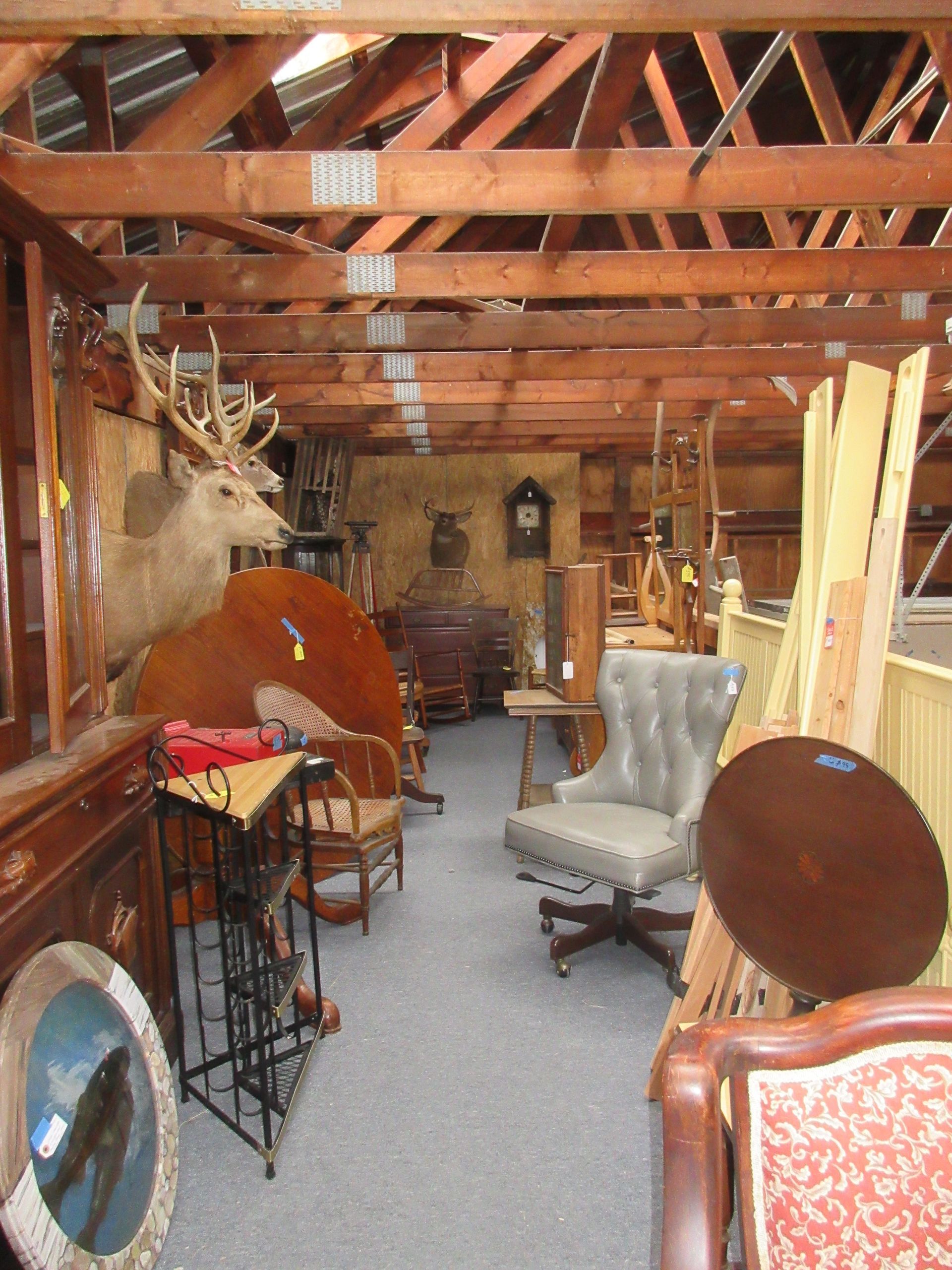 Interior of a storage building filled with various antique furniture pieces.