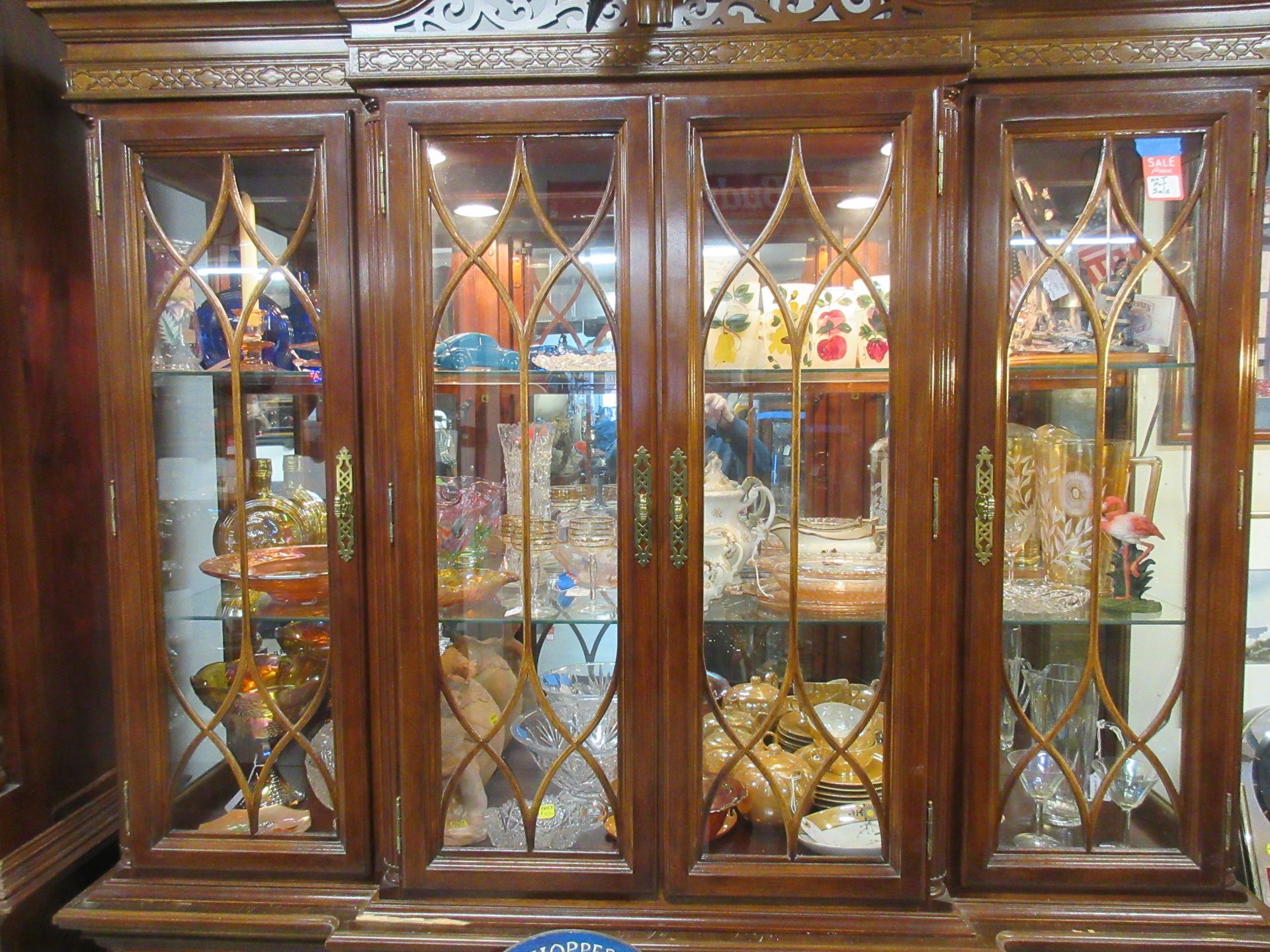Wooden curio cabinet with glass doors, displaying glassware and collectibles.