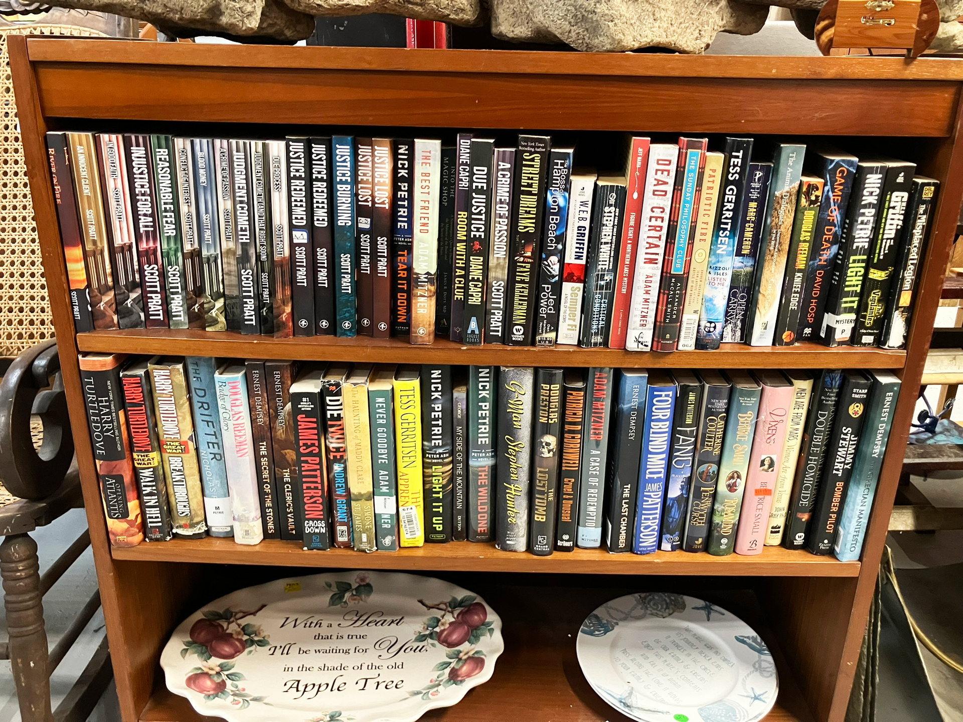 Wooden bookshelf filled with DVDs. Two shelves display movies, below are decorative plates.