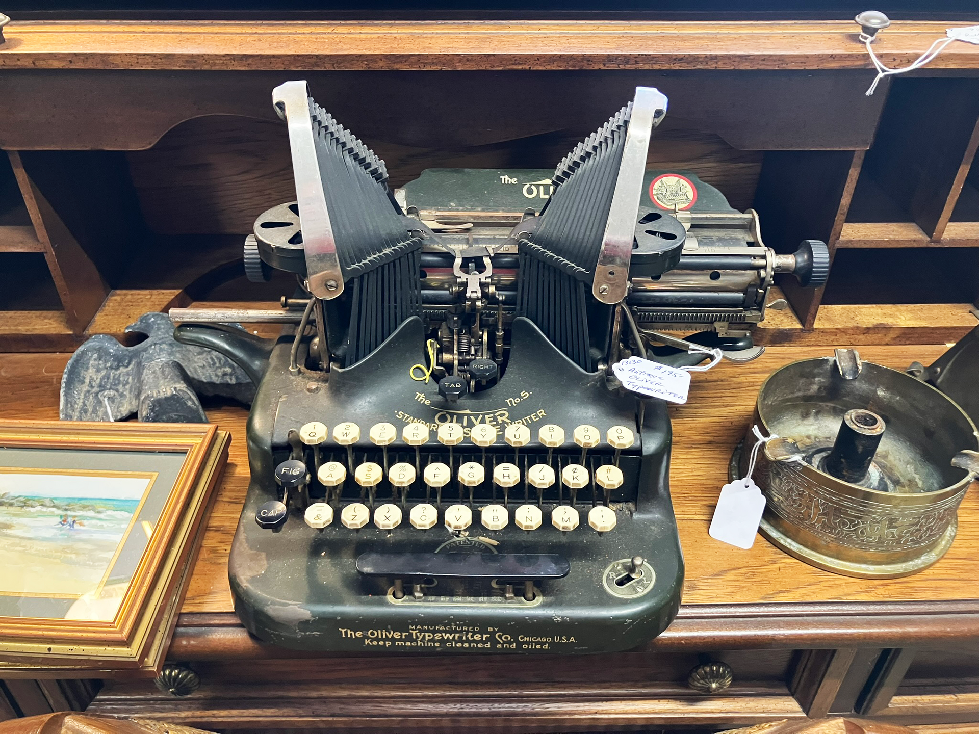 Antique green typewriter on a wooden surface, with white keys and metal parts.